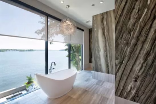 Modern luxury smart bathroom in Boca Raton featuring a standalone soaking tub, integrated lighting, and large windows with automated privacy shades.
